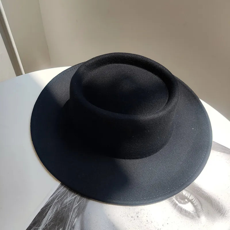 Black fedora hat on a white surface with a neutral background
