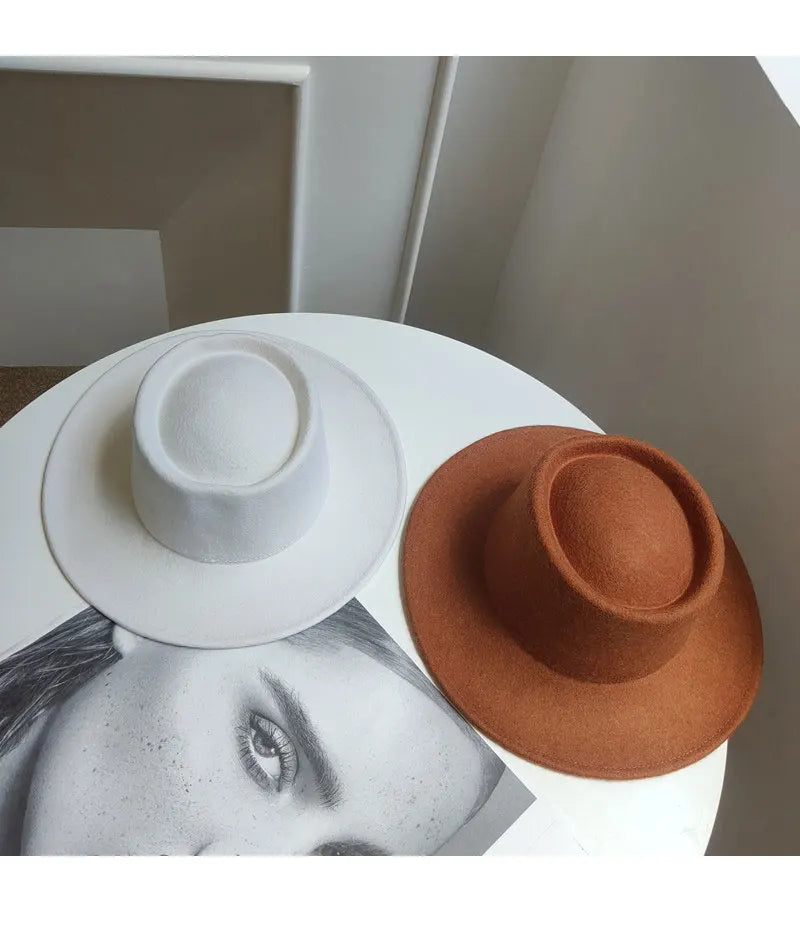 Two hats, one white and one brown, on a surface with a blurred background.