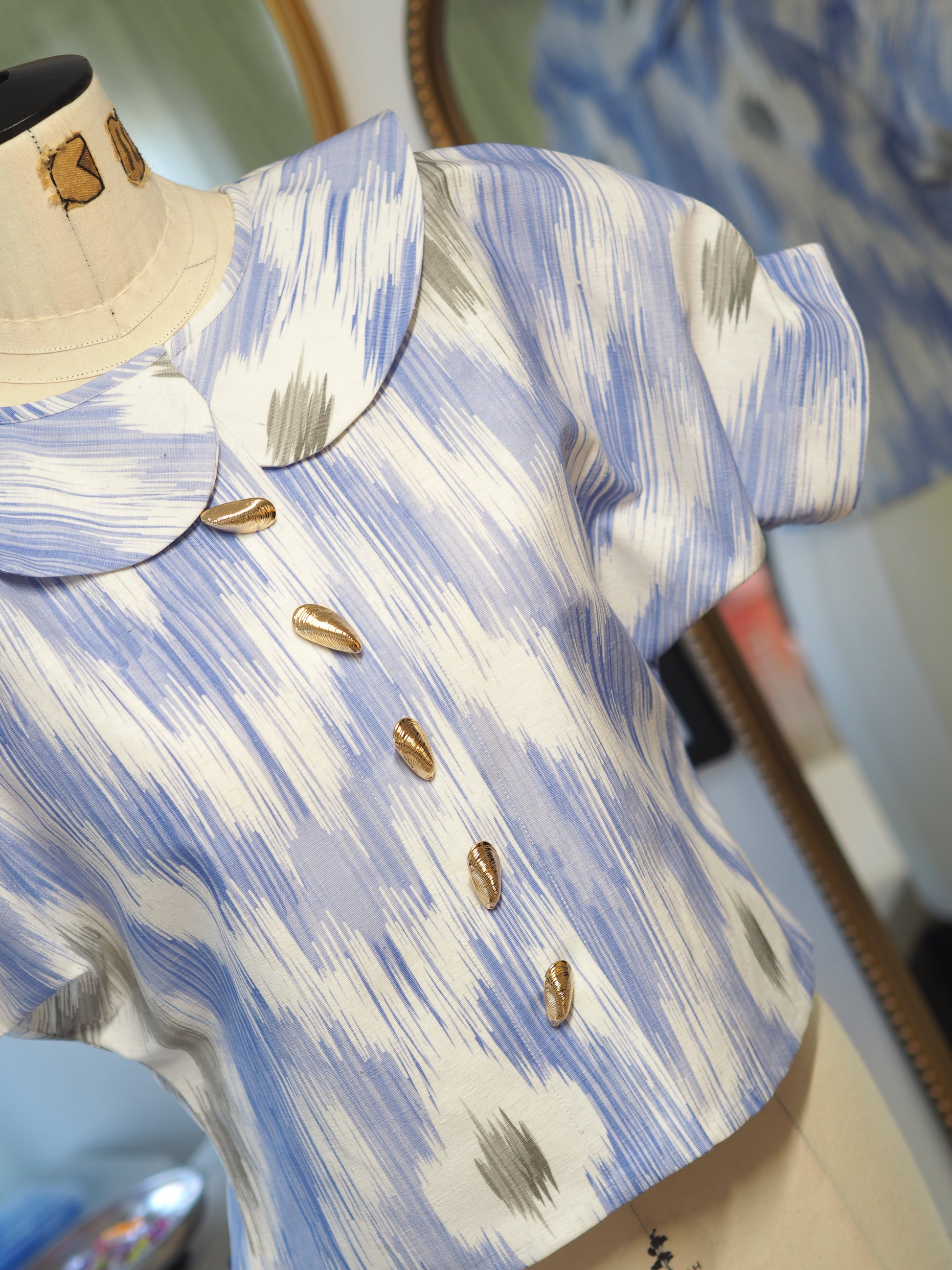 Close-up of a patterned fabric with gold buttons on a blue and white background.