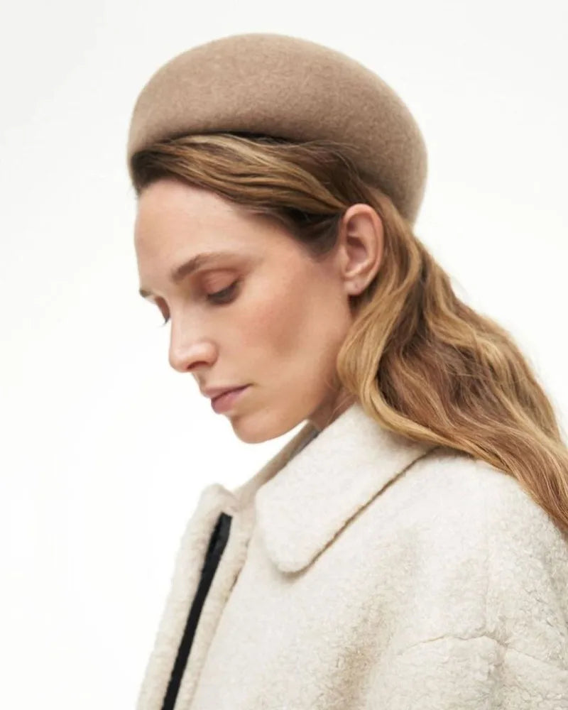Woman wearing a beige beret and coat on a white background