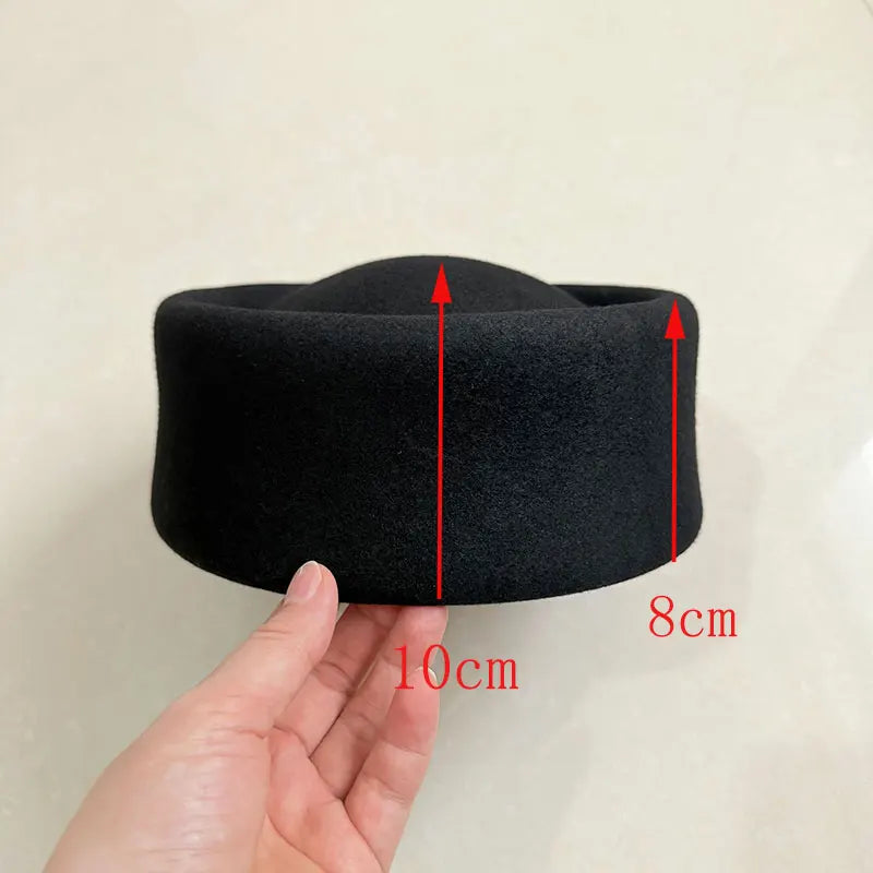 Black headband held by a hand with measurements indicated on a beige background